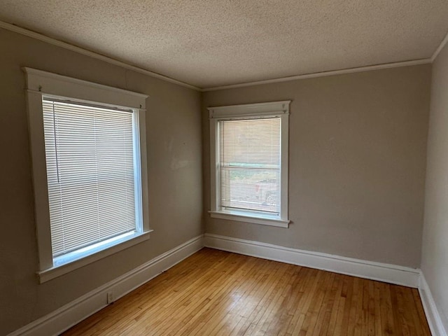 spare room featuring crown molding, a textured ceiling, and light hardwood / wood-style floors