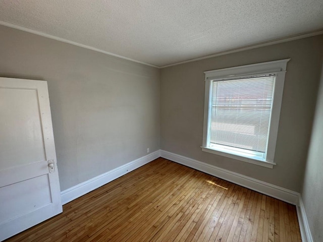 empty room featuring crown molding, a textured ceiling, and light wood-type flooring