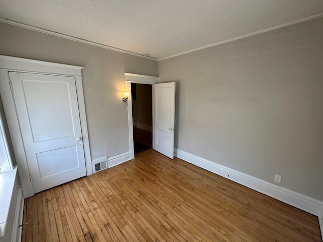 unfurnished bedroom featuring crown molding, light hardwood / wood-style floors, and a textured ceiling