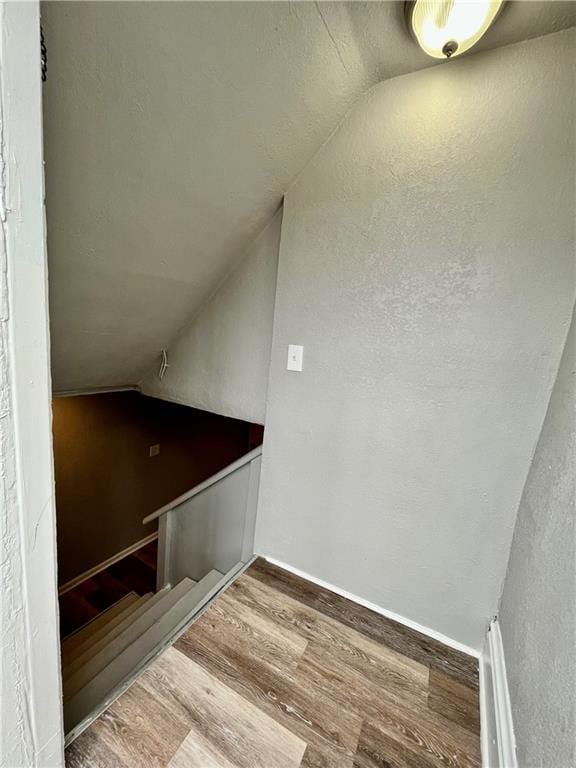 stairway featuring vaulted ceiling and hardwood / wood-style floors