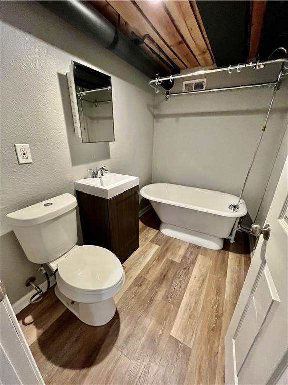 bathroom featuring hardwood / wood-style flooring, vanity, toilet, and a tub