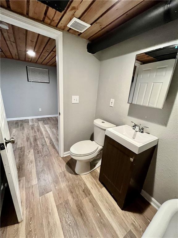 bathroom featuring wood-type flooring, vanity, wood ceiling, and toilet