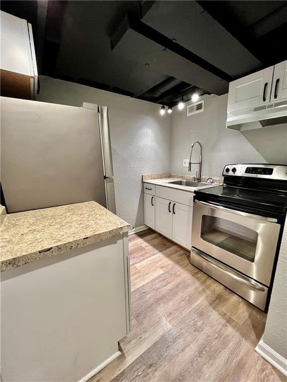 kitchen featuring sink, light hardwood / wood-style floors, white cabinets, and appliances with stainless steel finishes