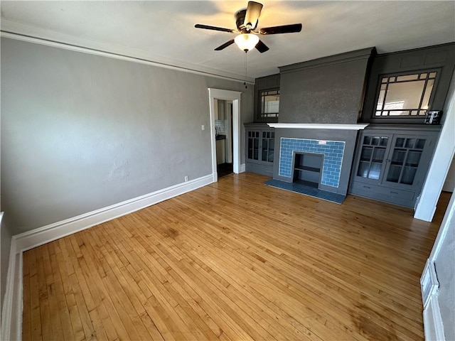 unfurnished living room with hardwood / wood-style floors, crown molding, a tile fireplace, and ceiling fan