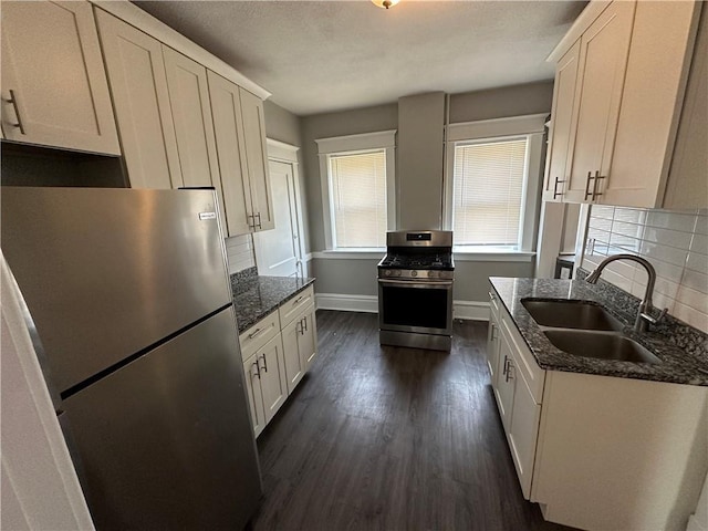 kitchen with sink, appliances with stainless steel finishes, dark hardwood / wood-style floors, dark stone counters, and decorative backsplash