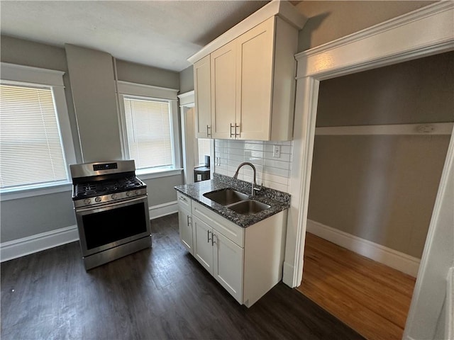 kitchen with sink, white cabinetry, backsplash, stainless steel range with gas stovetop, and dark stone counters