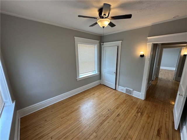 unfurnished bedroom with crown molding, ceiling fan, light hardwood / wood-style floors, and a textured ceiling