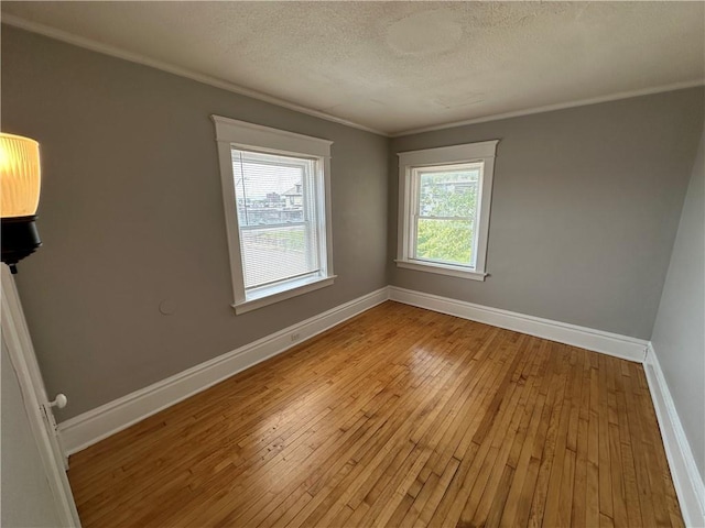 empty room featuring ornamental molding, a textured ceiling, and light hardwood / wood-style floors