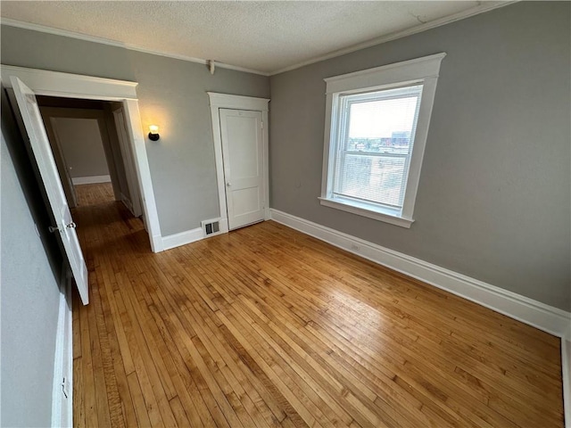 unfurnished bedroom with crown molding, a textured ceiling, and light wood-type flooring