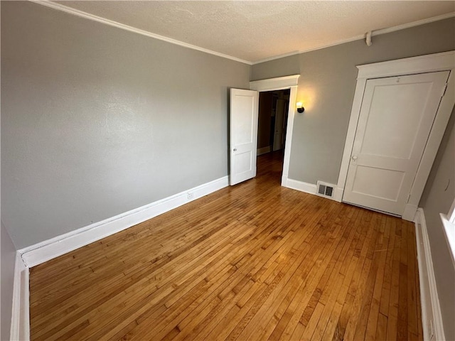 unfurnished bedroom featuring crown molding, light hardwood / wood-style floors, and a textured ceiling