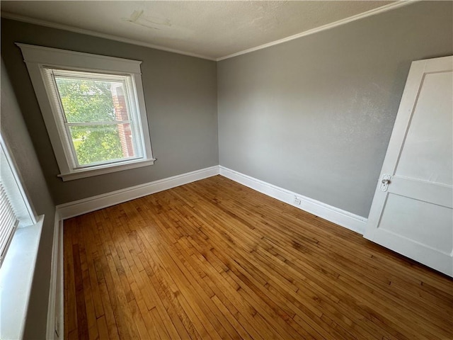 empty room featuring ornamental molding and hardwood / wood-style floors