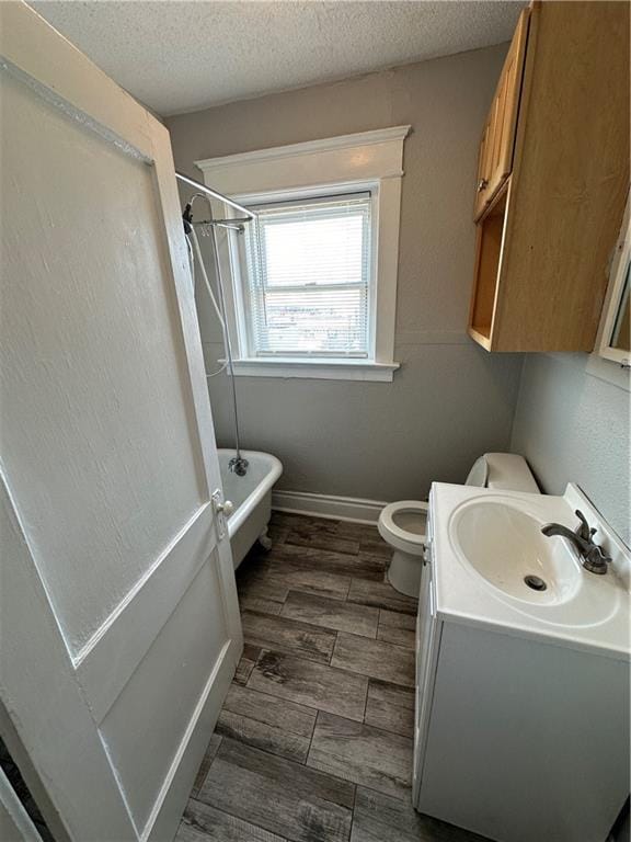 bathroom featuring vanity, toilet, a tub, and a textured ceiling