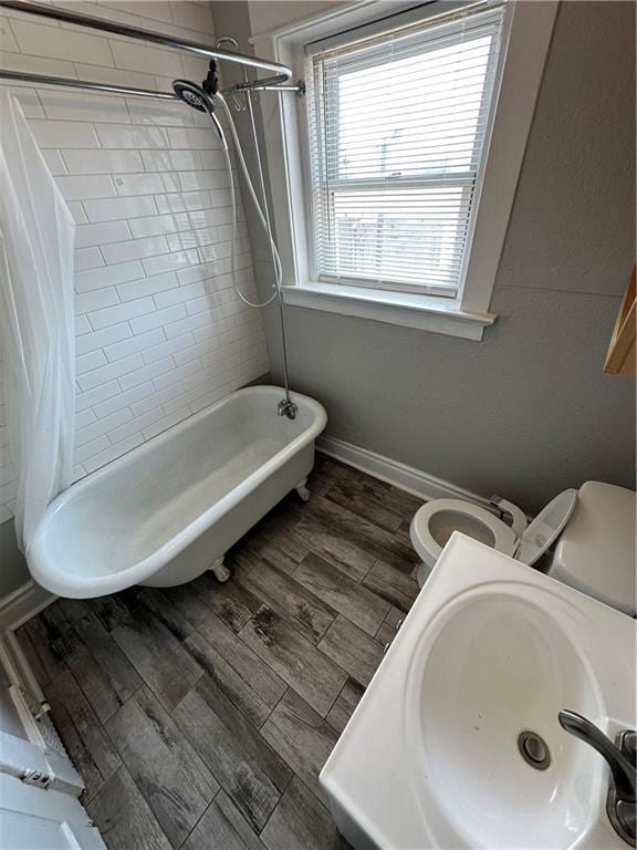 full bathroom with wood-type flooring, sink, shower / bathtub combination with curtain, and toilet