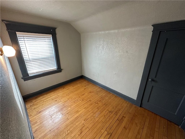 additional living space with lofted ceiling, light hardwood / wood-style floors, and a textured ceiling