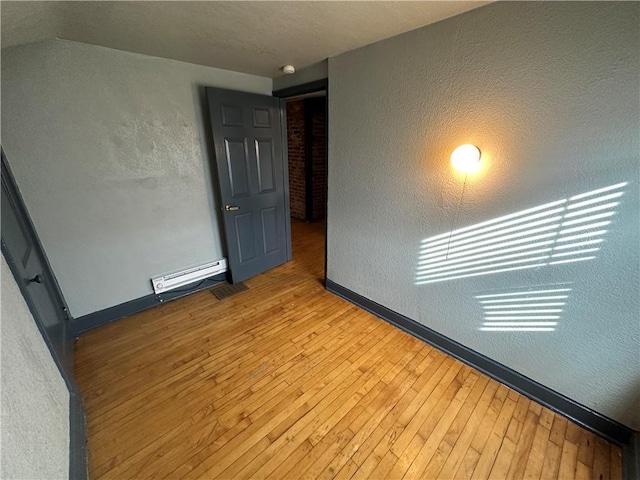 spare room with light wood-type flooring and a baseboard heating unit