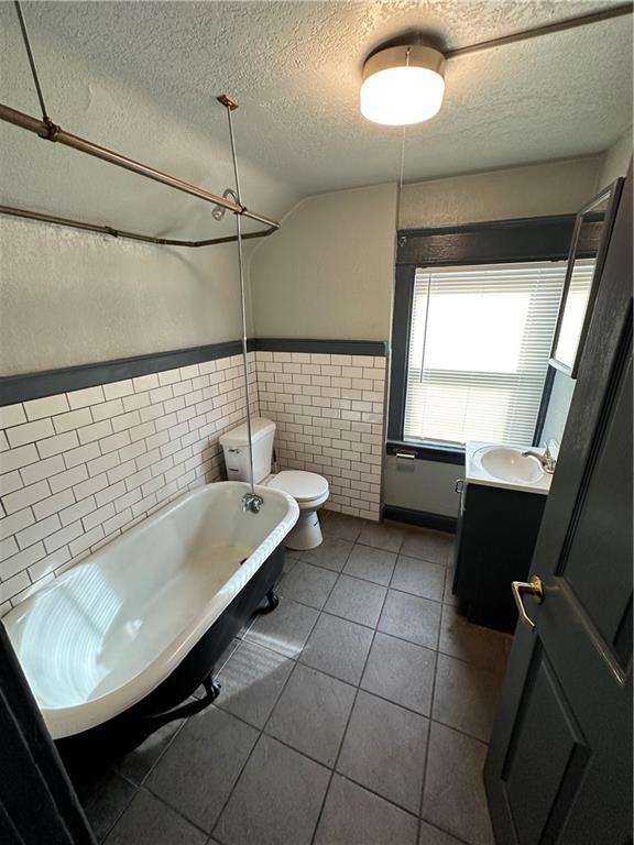 bathroom featuring tile patterned floors, toilet, a textured ceiling, vanity, and a bathtub