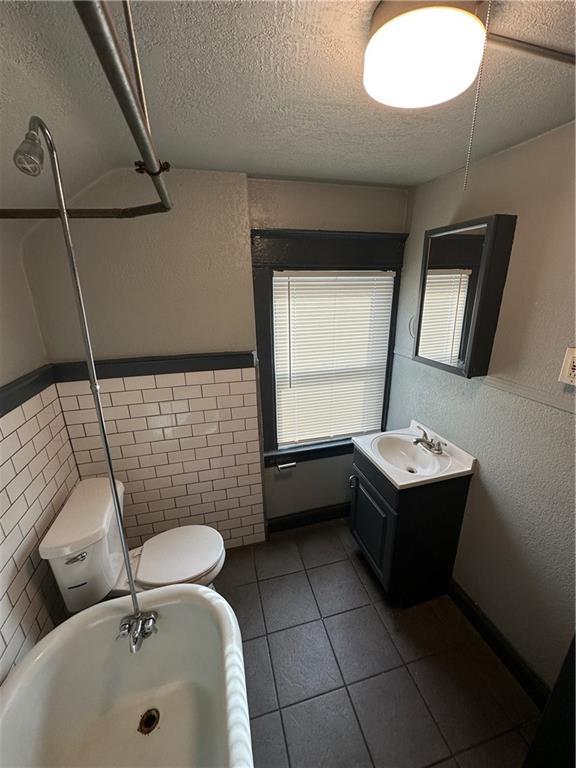 bathroom with tile patterned floors, vanity, toilet, and a textured ceiling