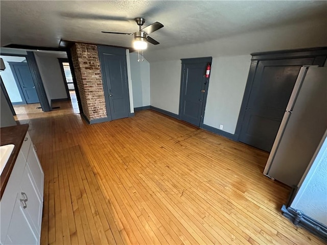 interior space with ceiling fan, a textured ceiling, and light hardwood / wood-style floors