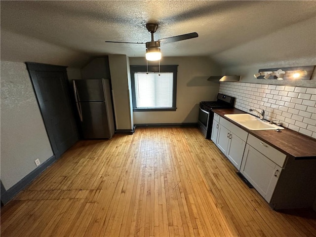 kitchen with butcher block countertops, lofted ceiling, sink, stainless steel appliances, and light wood-type flooring