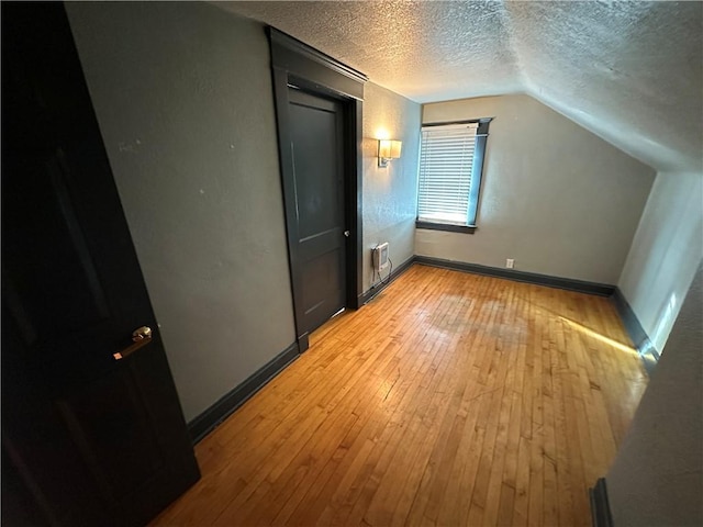 bonus room featuring vaulted ceiling, a textured ceiling, and light wood-type flooring