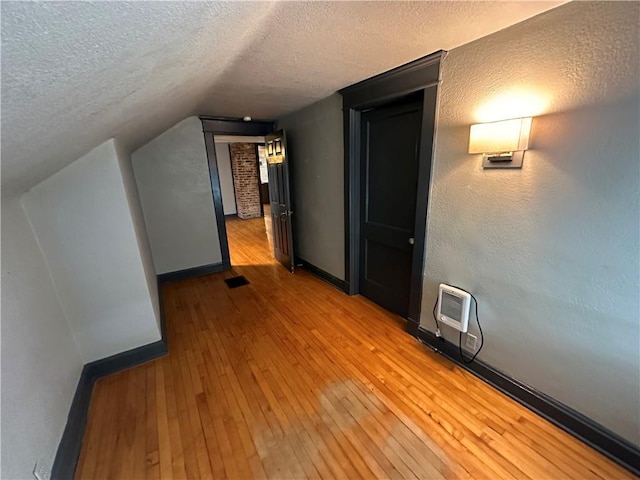 bonus room with lofted ceiling, a textured ceiling, and light hardwood / wood-style flooring