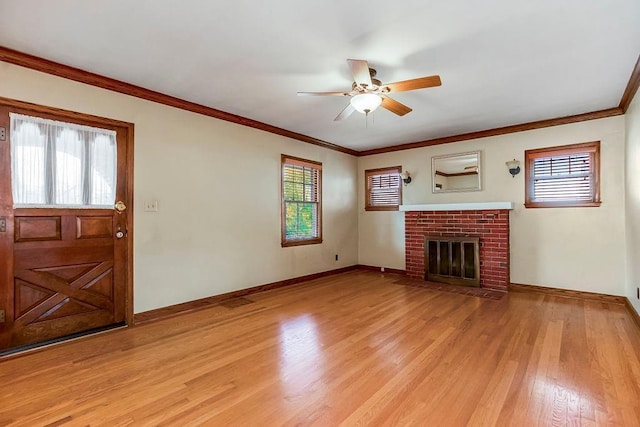 unfurnished living room featuring a brick fireplace, crown molding, light hardwood / wood-style floors, and ceiling fan