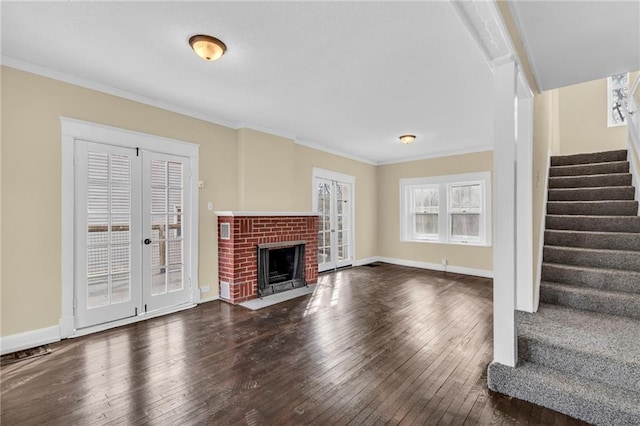 unfurnished living room with crown molding, a brick fireplace, dark wood-type flooring, and french doors