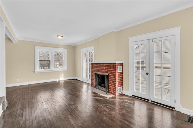 unfurnished living room featuring dark hardwood / wood-style flooring, a brick fireplace, ornamental molding, and french doors