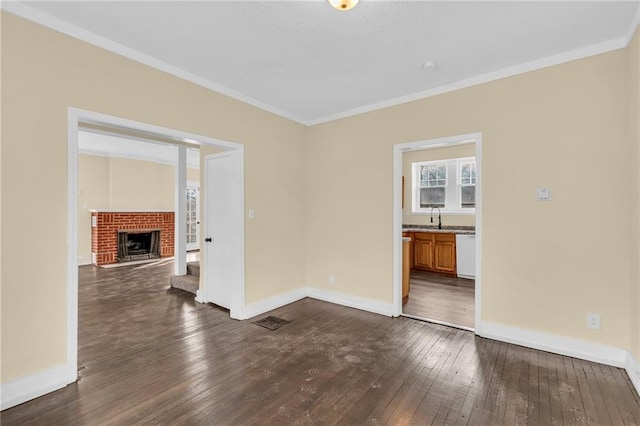 unfurnished room featuring crown molding, dark hardwood / wood-style flooring, sink, and a brick fireplace