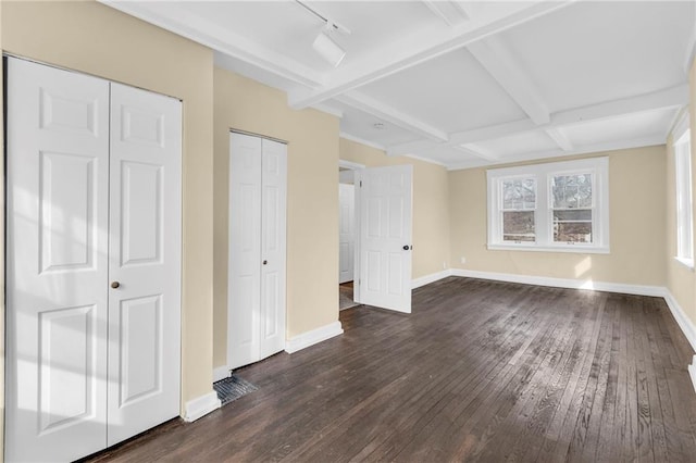 unfurnished bedroom with dark wood-type flooring, track lighting, coffered ceiling, and beam ceiling