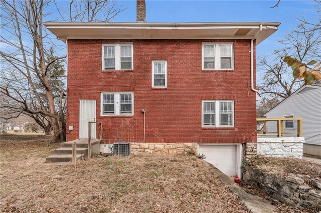 rear view of property featuring a garage and central air condition unit