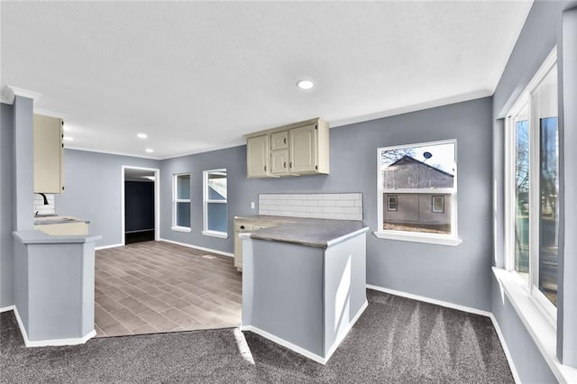 kitchen featuring crown molding, recessed lighting, cream cabinets, a sink, and baseboards