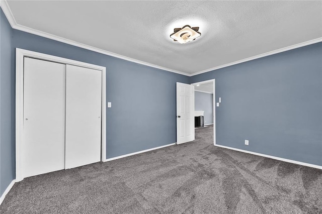 unfurnished bedroom featuring a textured ceiling, carpet floors, baseboards, a closet, and crown molding