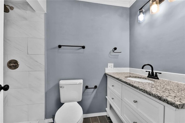 bathroom featuring baseboards, a tile shower, vanity, and toilet