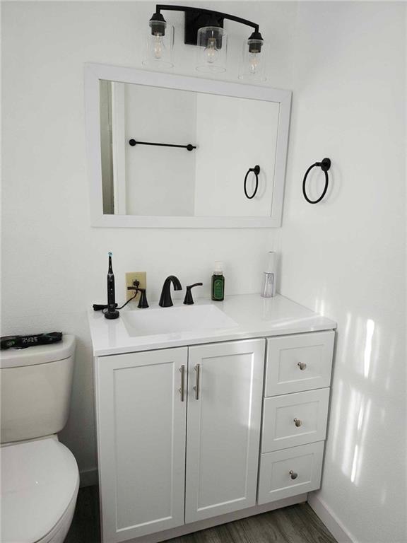 bathroom featuring hardwood / wood-style flooring, vanity, and toilet