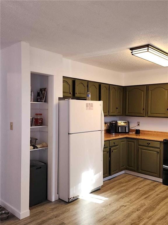 kitchen featuring range, a textured ceiling, white fridge, and light hardwood / wood-style flooring