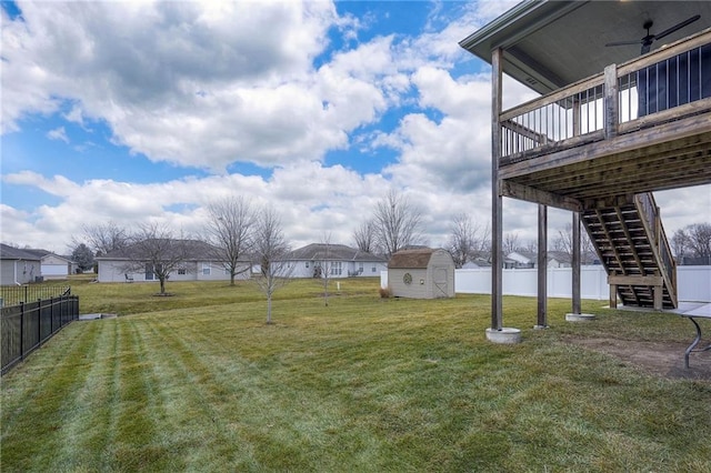 view of yard featuring a deck, ceiling fan, and a shed