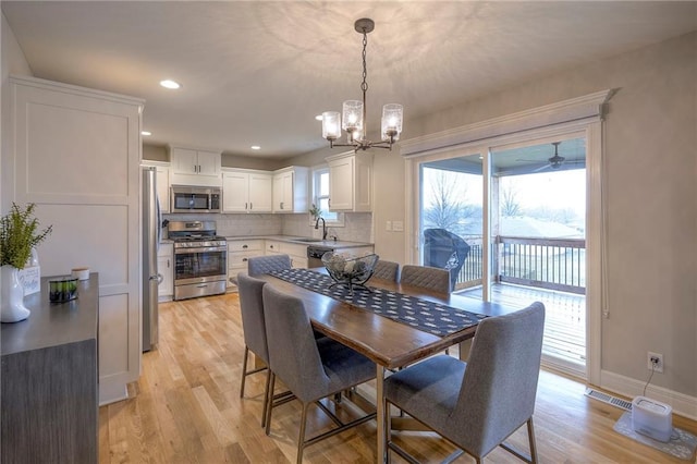 dining room with an inviting chandelier, sink, and light hardwood / wood-style floors