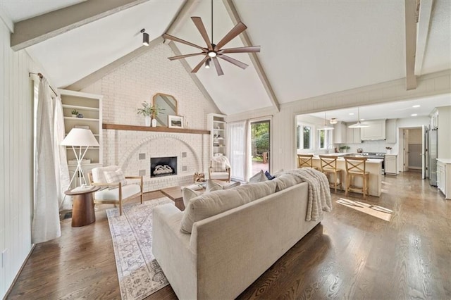 living room with beamed ceiling, ceiling fan, hardwood / wood-style flooring, and a fireplace