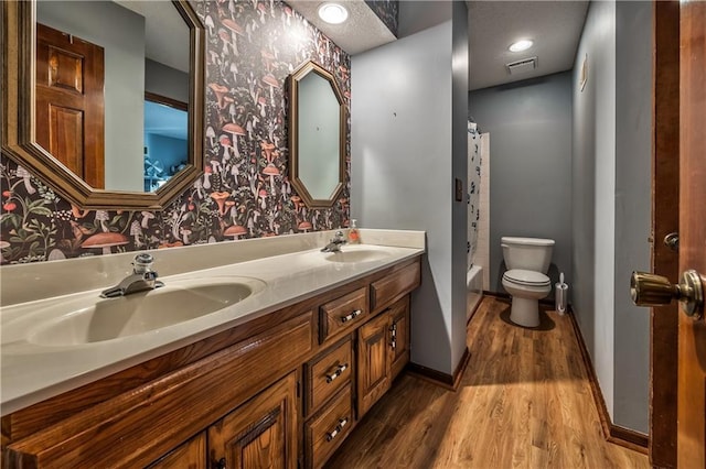 full bathroom featuring vanity, hardwood / wood-style floors, shower / tub combo, and toilet