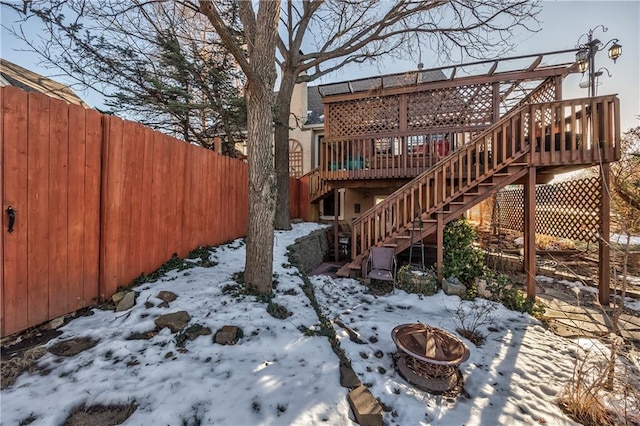 yard layered in snow with a wooden deck and an outdoor fire pit