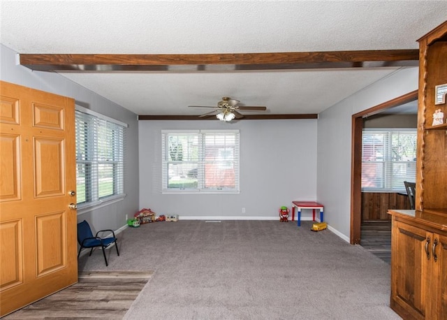 recreation room with beamed ceiling, carpet flooring, and ceiling fan