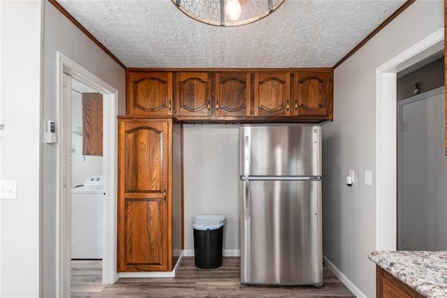 kitchen with washer / dryer, light wood-type flooring, stainless steel fridge, and a textured ceiling