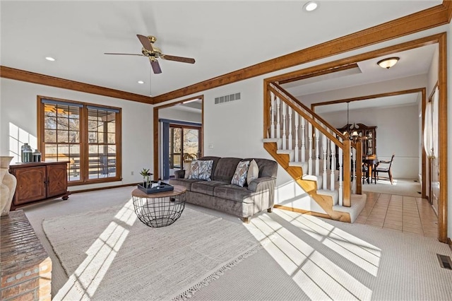 carpeted living room featuring ceiling fan with notable chandelier and ornamental molding