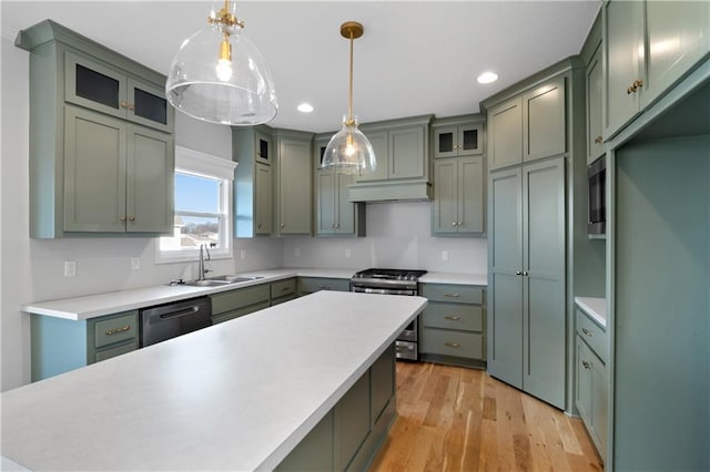 kitchen featuring sink, light hardwood / wood-style flooring, hanging light fixtures, stainless steel appliances, and green cabinetry