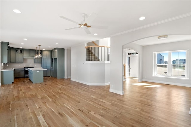 unfurnished living room with ceiling fan, ornamental molding, sink, and light hardwood / wood-style flooring