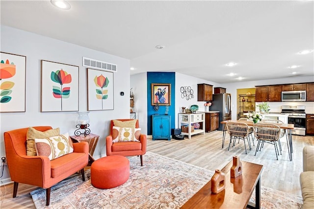 living room with baseboards, light wood-style flooring, visible vents, and recessed lighting