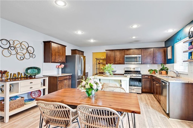 kitchen featuring light wood-style floors, appliances with stainless steel finishes, dark brown cabinets, and a sink