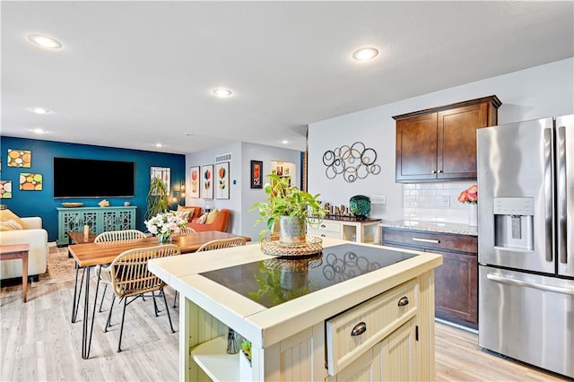 kitchen with stainless steel fridge, tasteful backsplash, a kitchen island, open floor plan, and light wood-type flooring