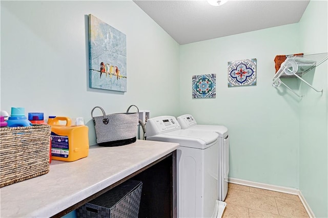 washroom with light tile patterned floors, laundry area, washer and clothes dryer, and baseboards